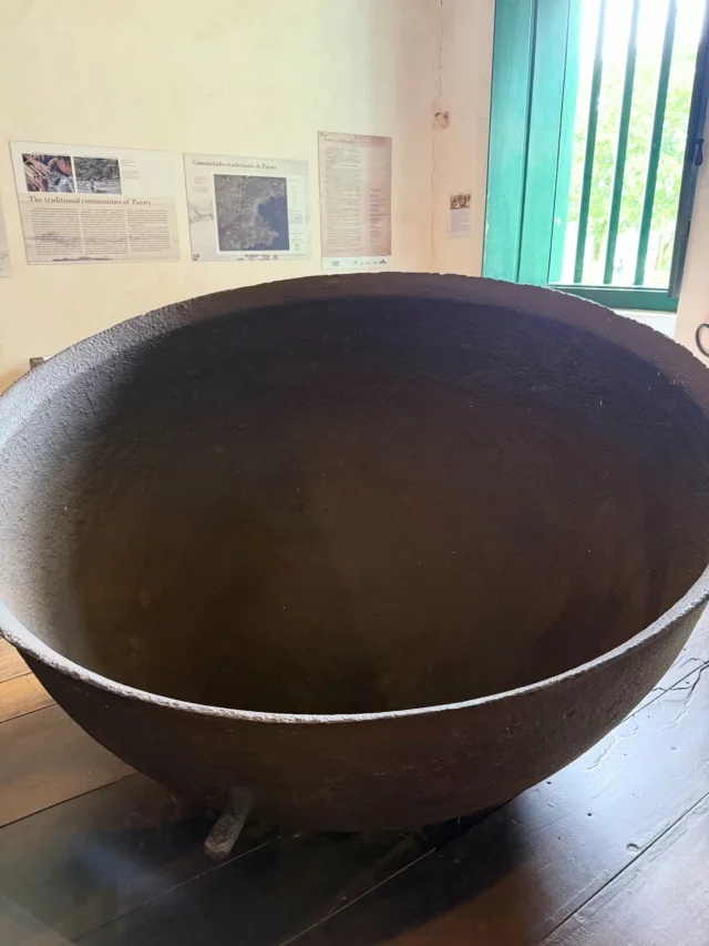 Esses caldeirões enormes que mais parecem banheiras gigantes , estão expostos no museu do Forte do Defensor Perpétuo , em Paraty . 
O caldo extraído da cana era fervido nesses tachos (de cobre ou ferro) em etapas sucessivas, para evaporar a água, concentrar o açúcar e formar o mascavo ou o açúcar refinado, que era então moldado em formas de barro. Esse método era comum nos engenhos brasileiros do século XVIII, período em que Paraty era um importante polo açucareiro, com mais de 250 engenhos na região, impulsionando a economia local antes do ciclo do ouro.
Os exemplares no museu, localizados no Quartel da Tropa, foram fabricados a partir de 1789 na fundição Low Moor, perto de Bradford, no norte da Inglaterra, e importados para o Brasil durante o período colonial.
Incapaz de olhar para eles e não imaginar o tamanho do tecido que poderia fazer Ecoprint se eu tivesse um desses em casa …